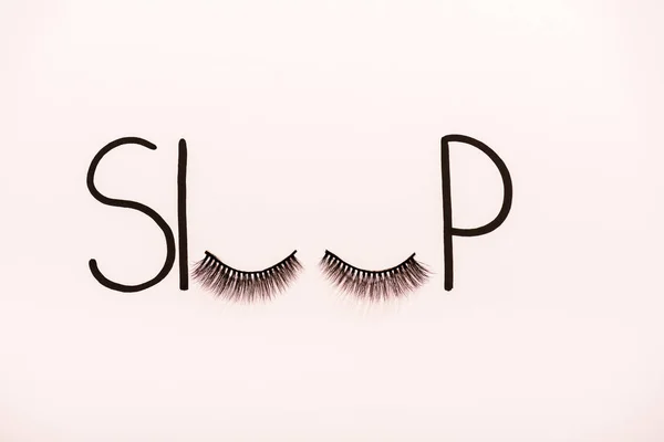 top view of word sleep made with fake eyelashes isolated on beige