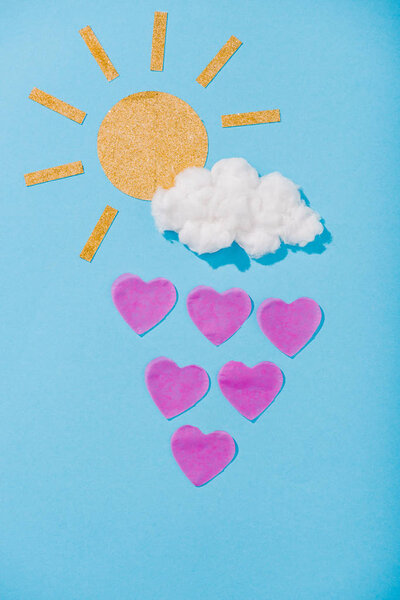 top view of paper sun, cotton candy cloud and heart-shaped raindrops on blue