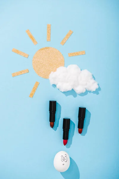紙の太陽 綿菓子の雲 驚いた顔の表情と青の口紅の雨滴のトップビュー — ストック写真