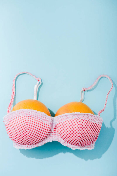 top view of bra with two oranges on blue with copy space, breasts concept
