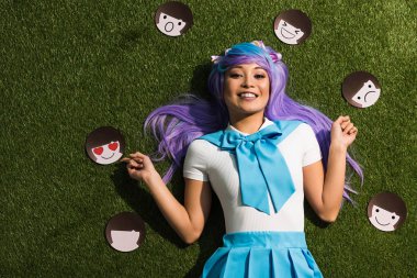 Asian anime girl in purple wig with emoticons lying on grass clipart