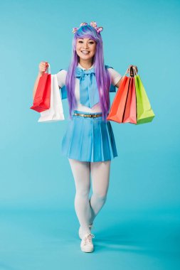 Mavi alışveriş çantaları tutan asya anime kız tam uzunlukta görünümü