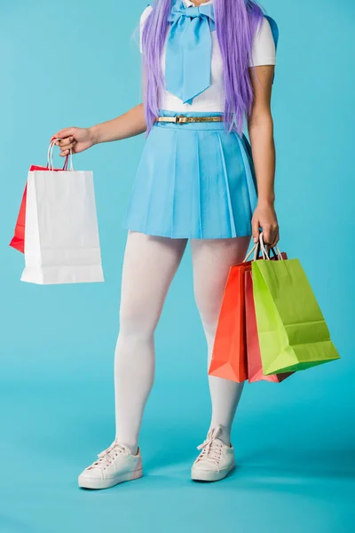 穿裙子和白色裤袜的女孩在蓝色上拿着购物袋的裁剪视图 — 图库照片