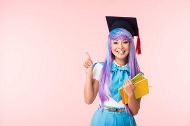 Akademik kap kitap tutan ve pembe izole parmak ile işaret gülümseyen asya anime kız