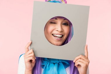 Gülümseyen asya anime kız pembe izole karton tutarak