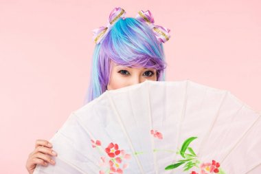 Asian anime girl in wig holding paper umbrella isolated on pink clipart