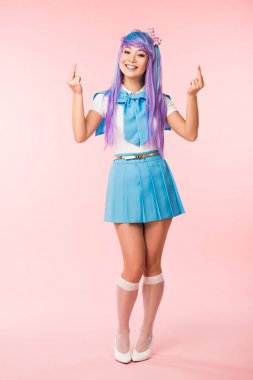 Pembe orta parmakları gösteren gülümseyen asya anime kız tam uzunlukta görünümü