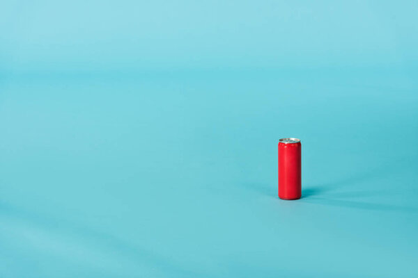 Red aluminum can with beverage on blue surface