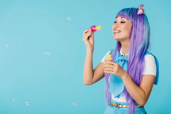 亚洲动漫女孩在紫色假发与肥皂泡隔离在蓝色 — 图库照片