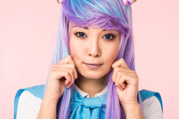 Pretty asian anime girl in purple wig posing isolated on pink