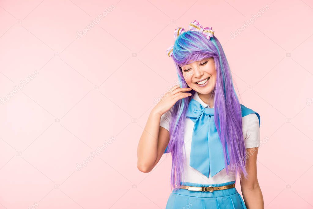 Pretty anime girl in wig smiling with closed eyes isolated on pink