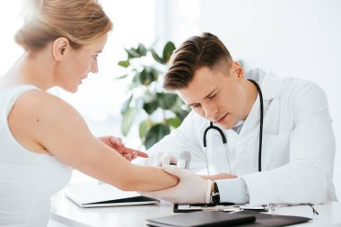 yakışıklı dermatolog dermatoskop tutarken çekici kadının elini muayene 