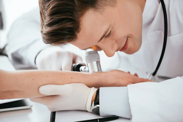 Dermatoskop Tutarken Kadının Elini Inceleyen Neşeli Bir Dermatolog — Stok fotoğraf