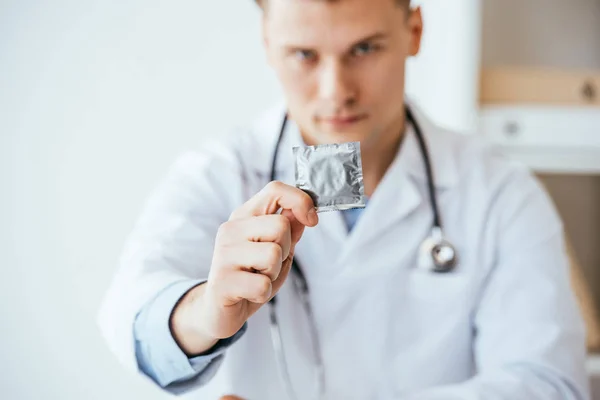Selektivní Zaměření Vážného Lékaře Bílém Plášti Který Drží Kondom Ruce — Stock fotografie