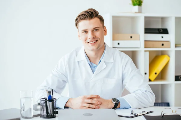 Cheerful Handsome Doctor White Coat Sitting Clenched Hands Clinic — Stock Photo, Image