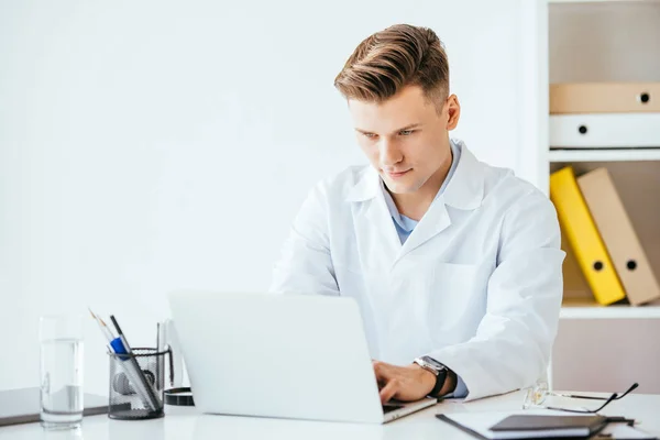 Schöner Arzt Weißen Kittel Während Laptop Der Klinik Benutzt — Stockfoto