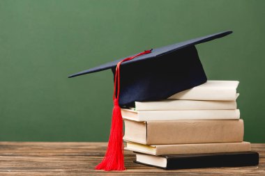 yeşil izole ahşap yüzey üzerinde kitap ve akademik kap