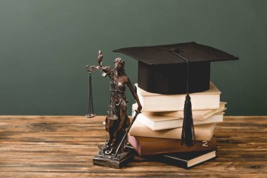 gri izole ahşap yüzey üzerinde themis heykelcik, kitap ve akademik kap