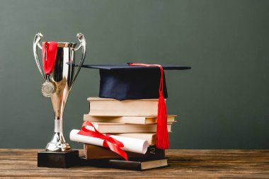 kitap, diploma, akademik kap, kupa kupası ve madalya ahşap yüzey üzerinde gri izole 