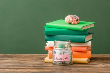 yeşil izole ahşap yüzeyüzerinde kitap, kumbara ve beyin