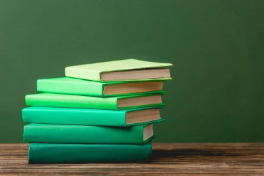yeşil izole ahşap yüzey üzerinde renkli kitap yığını