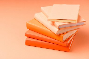 turuncu yüzeyüzerinde renkli ciltli kitap yığını