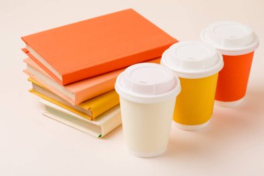 stack of books and colorful disposable cups on light surface clipart