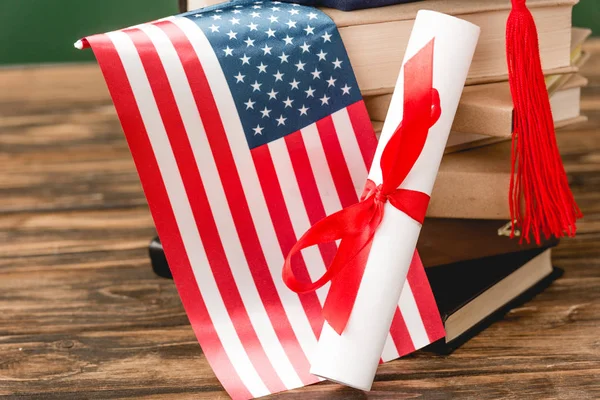木製の表面に本 卒業証書とアメリカの旗 — ストック写真