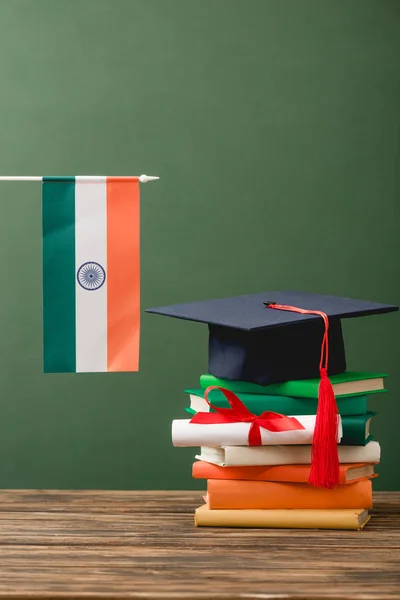 緑の上に隔離された木製の表面に本 卒業証書 学術帽とインドの旗 — ストック写真