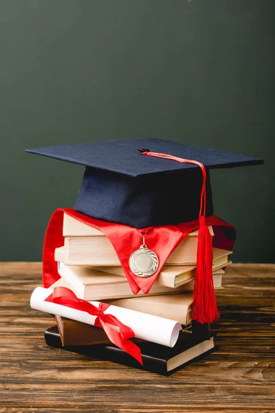 灰色に隔離された木製の表面の本 学術帽 メダル 卒業証書 — ストック写真