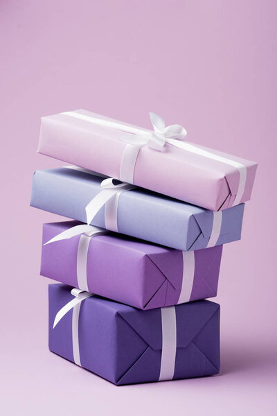 colorful gift boxes with white ribbons on purple surface