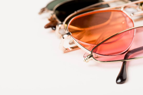 selective focus of stylish colorful sunglasses on white surface 