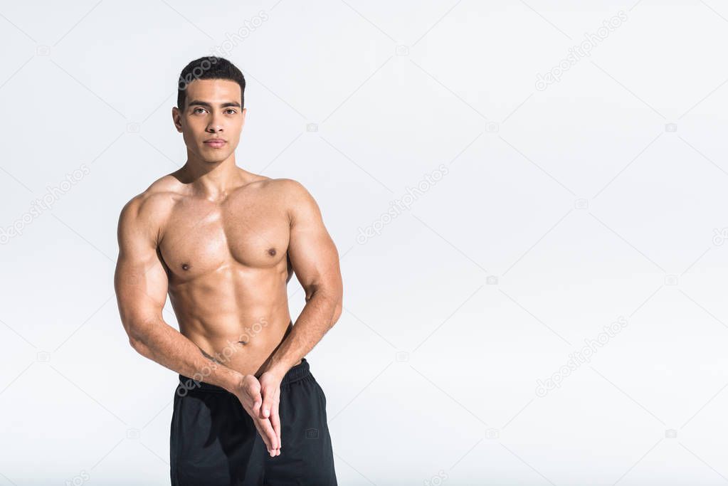 handsome athletic mixed race man with folded hands looking at camera on white