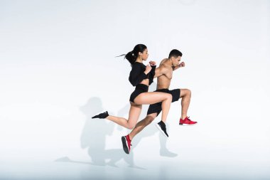 side view of sportive multicultural woman and man in sportswear and sneaker running on white background clipart