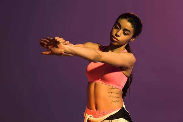 Pretty african american girl in pink sports bra warming up isolated on purple — Stock Image Pretty African American Girl Pink Sports Bra Warming Isolated Purple Stock Image