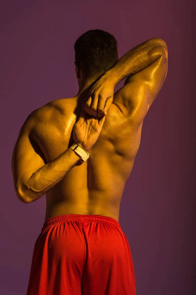 Visão Traseira Homem Esportivo Com Alongamento Tronco Muscular Fundo Roxo — Fotografia de Stock