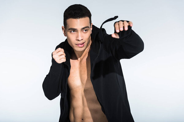 handsome mixed race man in black sports jacket warming up on white