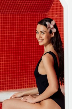spa merkezinde kamera bakarak saç çiçek ile güzel gülümseyen kadın