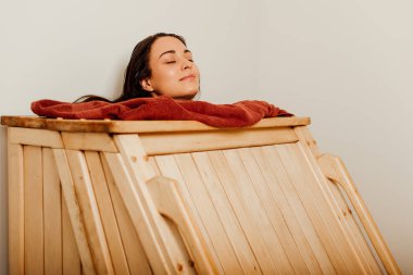 spa merkezinde kapalı gözlerle buhar banyosu alan gülümseyen kadın