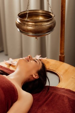 ayurvedik işlem sırasında shirodhara gemi altında yatan rahat genç kadın