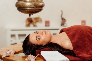 ayurvedik işlem sırasında shirodhara gemi altında yatan rahat genç kadın