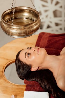 ayurvedik işlem sırasında shirodhara gemi altında yatan rahat genç kadın