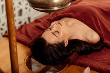 ayurvedik işlem sırasında shirodhara gemi altında yatan rahat genç kadın