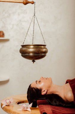 ayurvedik işlem sırasında shirodhara gemi altında yatan kadının yan görünümü