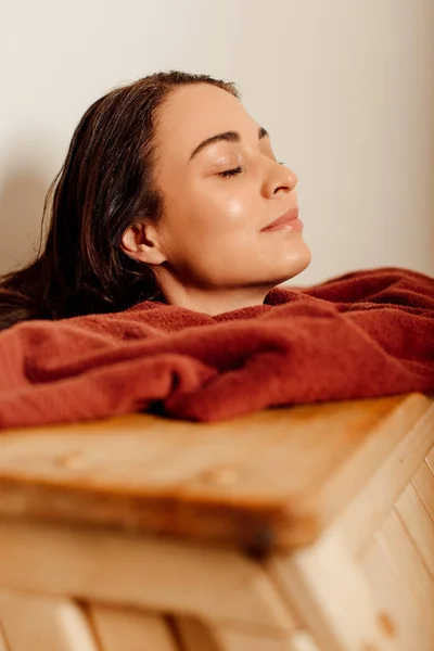 smiling woman taking steam bath with closed eyes in spa center