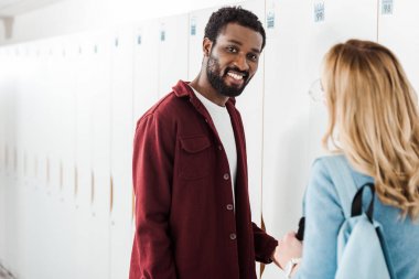 üniversitede dolap yakınında koridorda iki gülümseyen çok ırklı öğrenciler