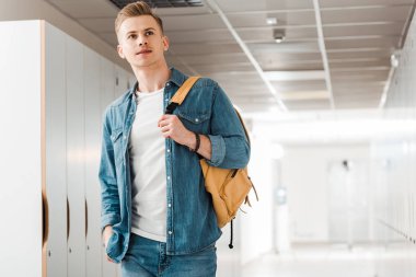 pensive student with backpack in corridor in university clipart