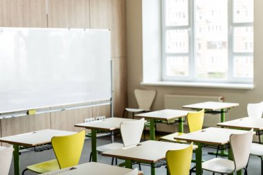 classroom with wooden desks, chairs, window and flipchart clipart