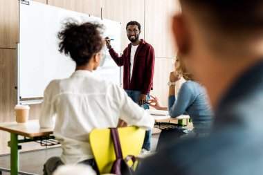 flipchart yakınında duran gözlük le gülümseyen afrikalı Amerikalı öğrenci