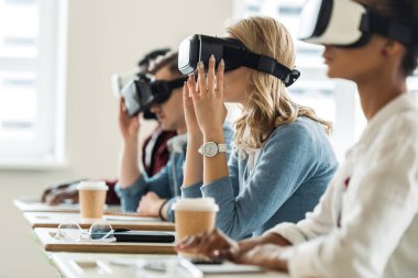 selective focus of multiethnic students using vr headsets in university clipart
